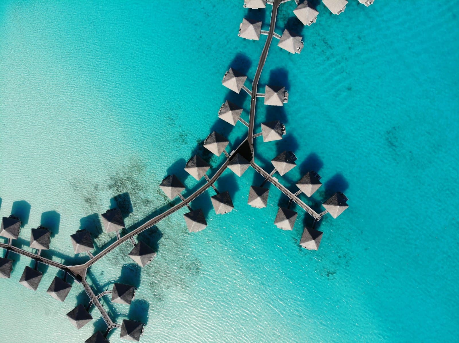 Overwater bungalows reaching into a turquoise lagoon in French Polynesia